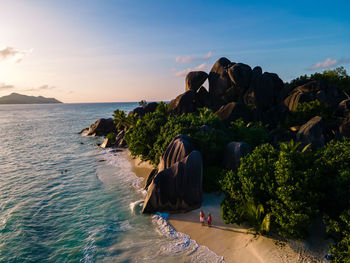 Rear view of people on beach against sky during sunset