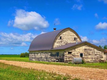 Barn on field by building against sky