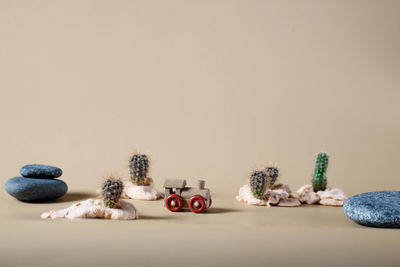 Background image of wooden toy steam locomotive in desert with stones and cactuses on beige backdrop