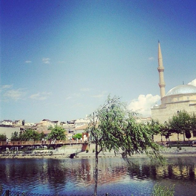 architecture, water, built structure, building exterior, tree, waterfront, reflection, sky, river, blue, religion, lake, place of worship, clear sky, travel destinations, spirituality, nature, outdoors, tranquility, day