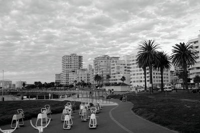 Vehicles on road by buildings in city against sky