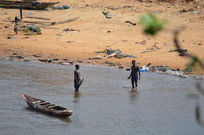 High angle view of shirtless men by dugout canoe on river