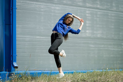 Full length of woman stretching while walking on grass