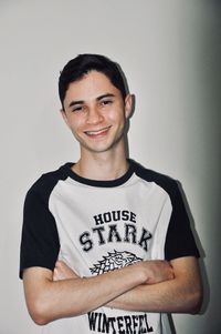 Portrait of smiling young man standing against wall