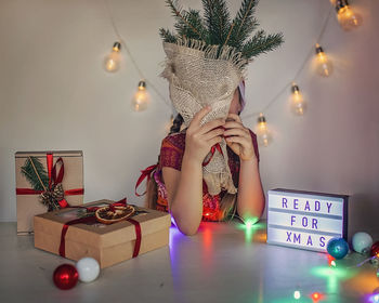 Portrait of young woman holding christmas tree at home