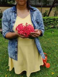 Midsection of woman holding red flowering plants