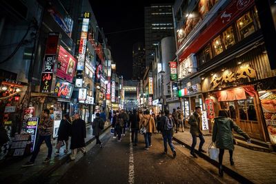 People walking on illuminated street at night