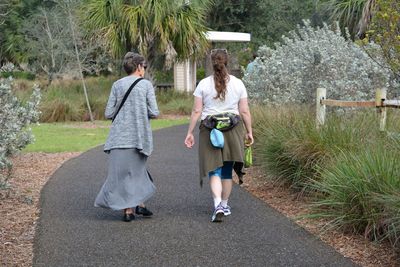 Women walking on road amidst trees