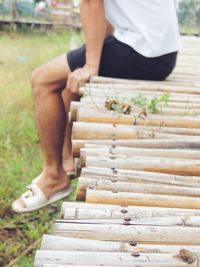 Low section of man sitting on wood