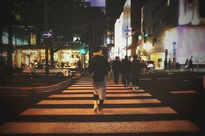 People walking on city street at night