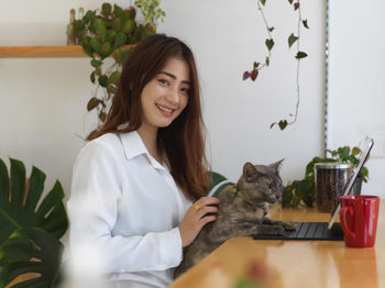 Portrait of smiling young woman with cat