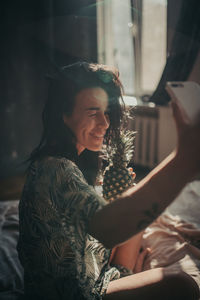 Side view of a smiling young woman sitting at home