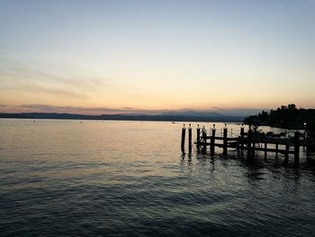 Pier in sea at sunset