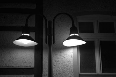 Low angle view of illuminated light bulb hanging on wall