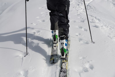 Low section of man standing on snow covered mountain