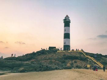 Lighthouse on landscape against sky during sunset