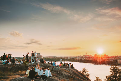 People on beach against sky during sunset