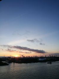 Silhouette of boats in river against sky during sunset