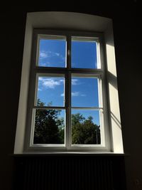 Low angle view of trees against sky seen through window