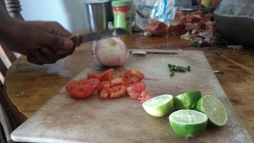 Hand holding vegetables on cutting board