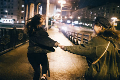 Smiling friends walking on road in city at night