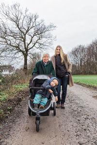 Woman with daughter and mother on dirt field during winter