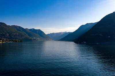 Scenic view of lake by mountains against blue sky
