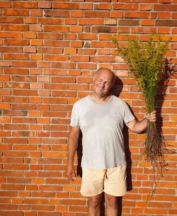 Full length of man standing against brick wall