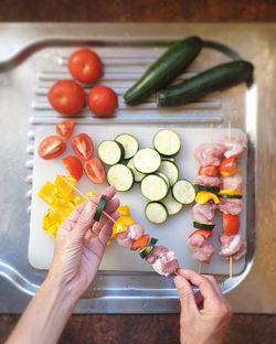 High angle view of person preparing skewers shish kebab