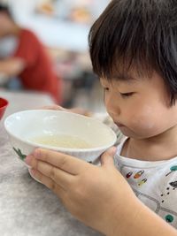 Asian boy looking at soup in a white china bowl