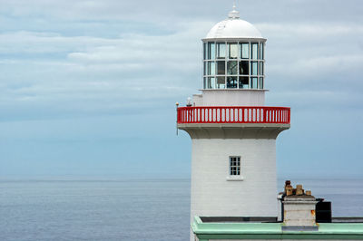 Lighthouse by sea against sky