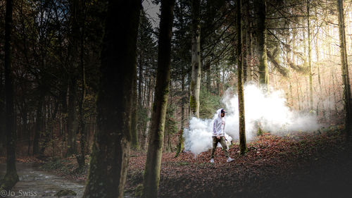 Full length of man walking in forest by smoke