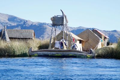 Houses by lake and mountains against clear sky