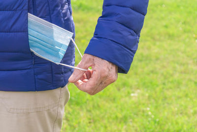 Midsection of man holding umbrella on field