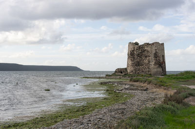 Stone wall by sea against sky