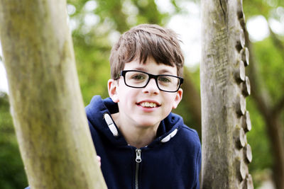 Portrait of boy wearing eyeglasses by tree trunk