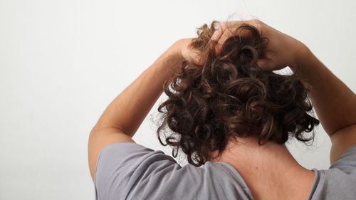 Rear view close-up of man tying hair against white background