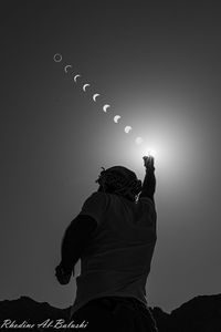 Rear view of man holding illuminated light against sky at night