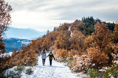 Rear view of people walking on snow covered mountain