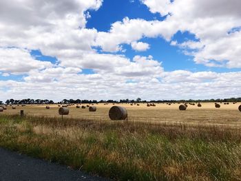 Hay bales on field against sky