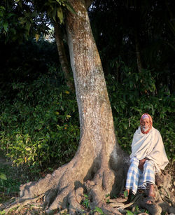 Rear view of man sitting on tree