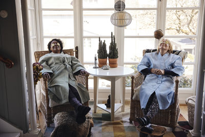 Multiracial female friends with cucumber slices on eyes relaxing together at home