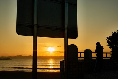 Silhouette people looking at sea against sky during sunset