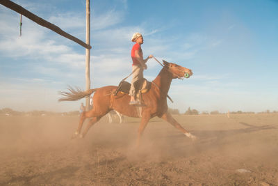 Full length of person riding horse on land against sky