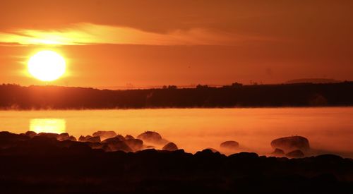 Scenic view of silhouette rocks against sky during sunset