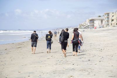 Rear view of people walking on beach