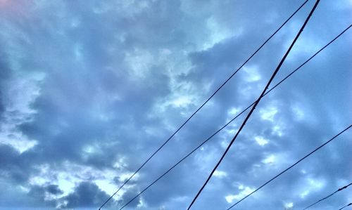 Low angle view of power lines against cloudy sky