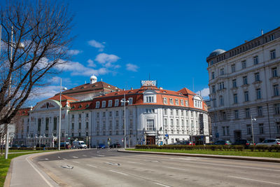 Road by buildings against blue sky