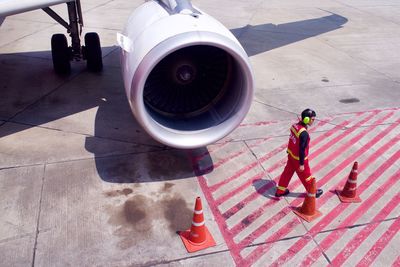 High angle view of man walking by airplane engine at runway