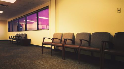 Empty chairs and table against window